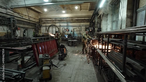 A welder and a metal cutter in the workshop of a metalworking workshop prepares steel parts. Sparks.Workers work at the factory, the welder prepares, the workflow in the shop