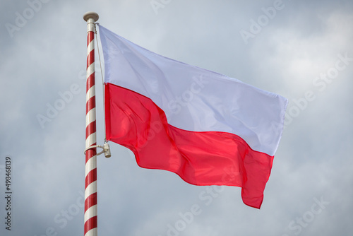 Polish flag flutters in the wind against the cloudy sky