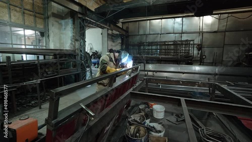 A worker cooks metal on a welding machine in production. a worker with a welding machine to cook parts