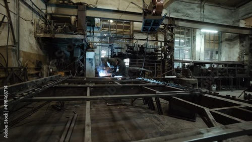 A worker cooks metal on a welding machine in production. a worker with a welding machine to cook parts