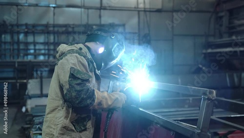 A worker cooks metal on a welding machine in production. a worker with a welding machine to cook parts