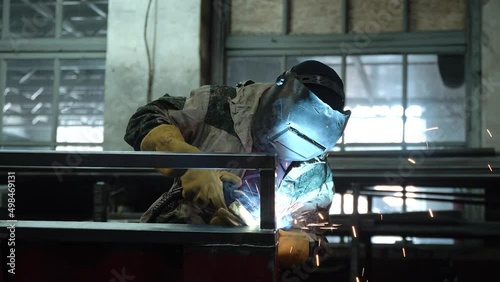 A worker cooks metal on a welding machine in production. a worker with a welding machine to cook parts