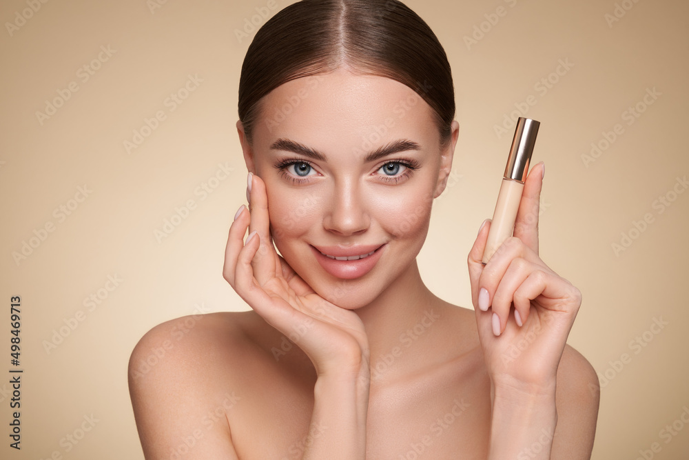 Portrait beautiful young woman with clean fresh skin. Model with foundation makeup bottle. Cosmetology, beauty and spa Portrait beautiful young woman with clean fresh skin. Model with foundation makeup bottle. Cosmetology, beauty and spa