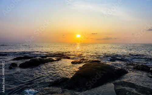 Sunset on tropical island in south of Thailand, peaceful rock beach with beautiful sunset