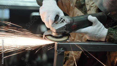 Heavy Industry Engineering Factory Interior with Industrial Worker Using Angle Grinder and Cutting a Metal Tube. Contractor in Safety Uniform and Hard Hat Manufacturing Metal Structures. a worker with