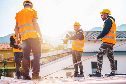 Team of technical workers work on the roof of a house
