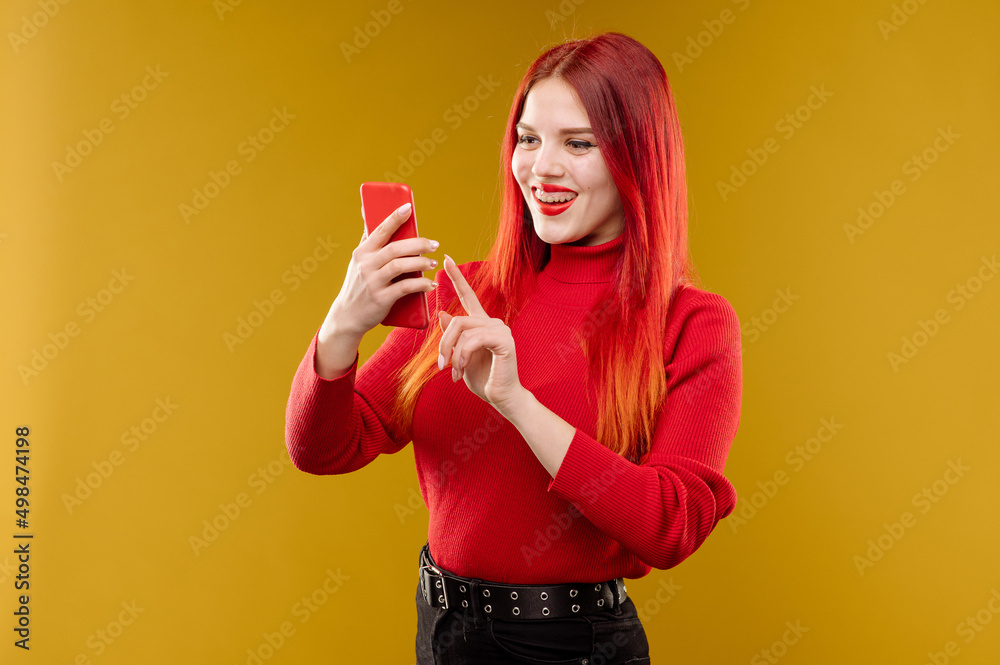 Glamour woman with red hair using smartphone on yellow background Glamour woman with red hair using smartphone on yellow background