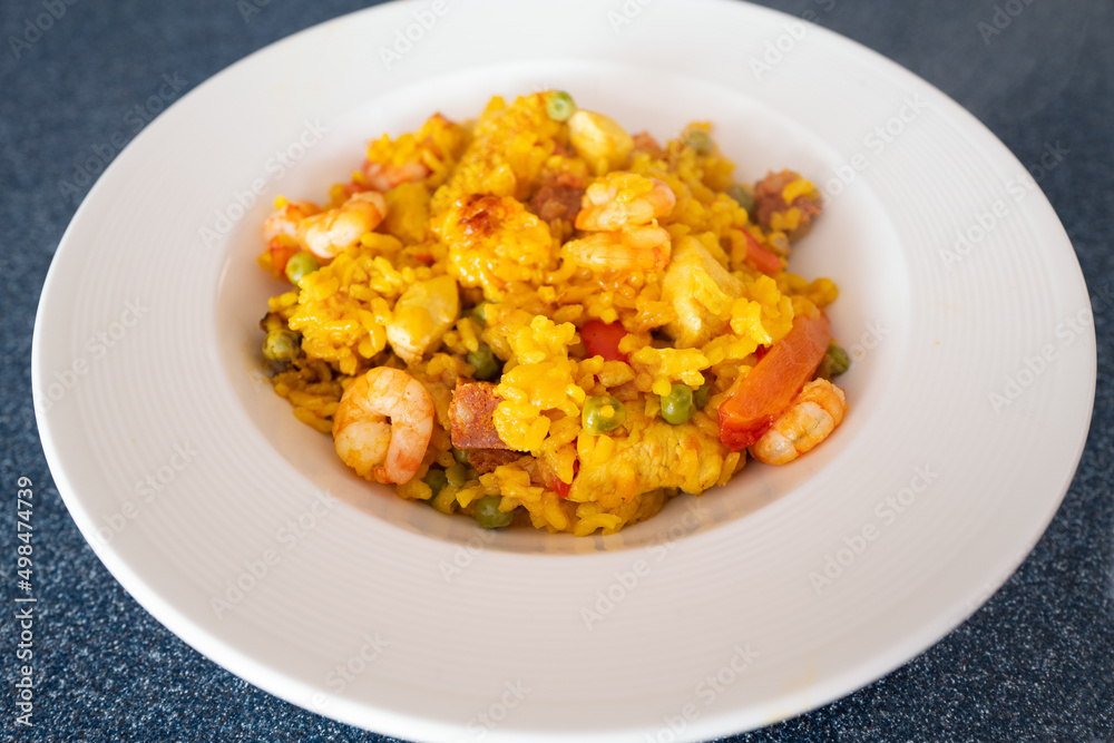 Prawns and chorizo sausage in a home made rice paella dish. There is also chicken with onion, peas and peppers in the meal. It is served in a round white dish. Prawns and chorizo sausage in a home made rice paella dish. There is also chicken with onion, peas and peppers in the meal. It is served in a round white dish.