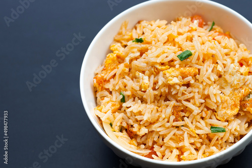 Fried rice in white bowl on dark background.