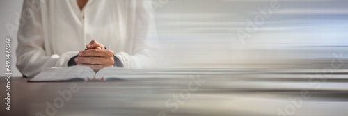 Mid section of a woman praying over a holy bible against grey background with copy space