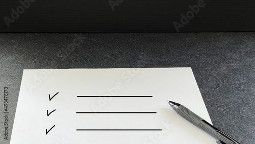 黒いテーブルの上のチェックリストの白い用紙とペン photo