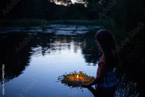 Young girl with wreath going to the river to set it float down the river, kapala night magic, pagan traditions. Girl swims in river late at night photo