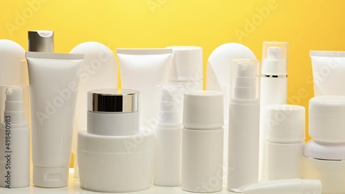 jar, bottle and empty white plastic tubes for cosmetics on a yellow background. Packaging for cream, gel, serum, advertising and product promotion
