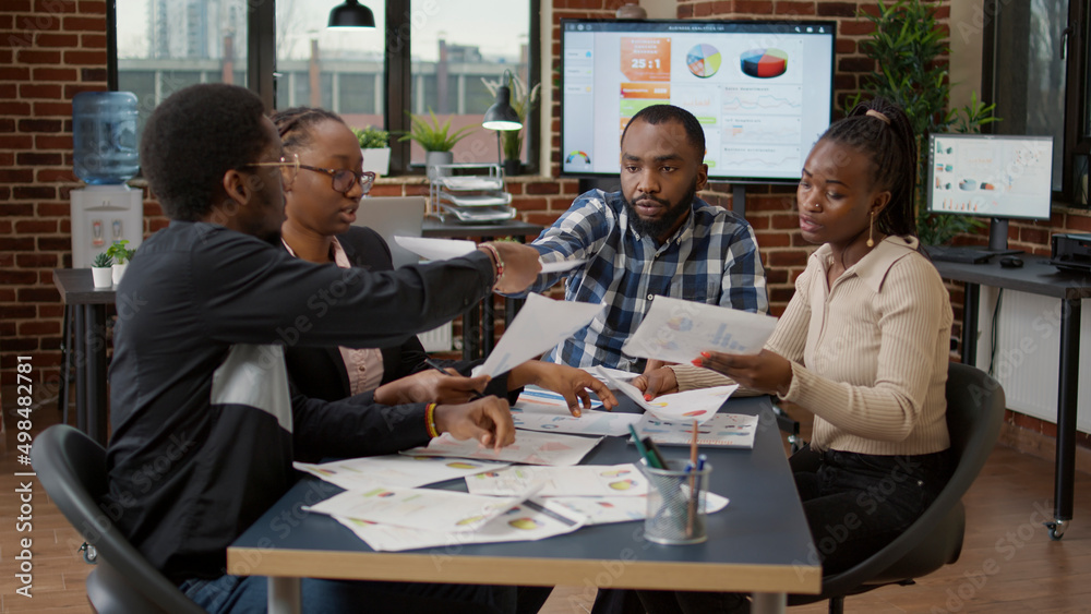 African american startup team doing teamwork to create business analysis with data charts and statistics graphs on documents. Workers analyzing sales diagram and doing presentation research.