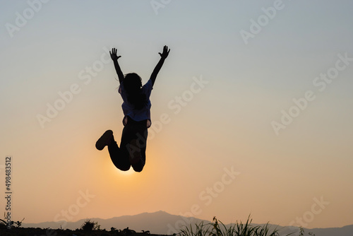 Silhouette of happy child jumping playing on mountain at sunset time