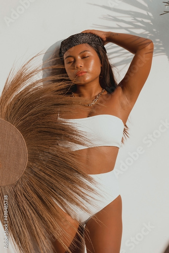 Young Female Asian in a White Swimsuit posing with a Bohemian Fan