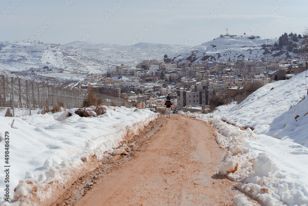 Military road near Israel-Syria border, ceasefire lines 1974 undof line alpha. On a background of snow-capped mountains and Majdal Shams village on Hermon highest Israel mountain