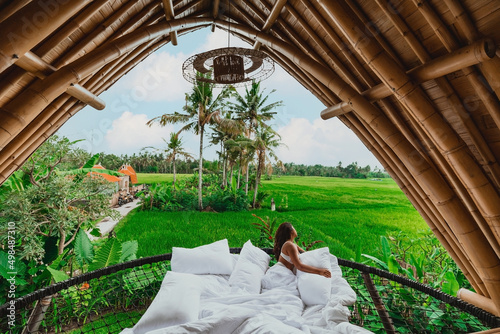 young asian female in a luxury bamboo eco villa overlooking the bali rice fields and coconut trees photo