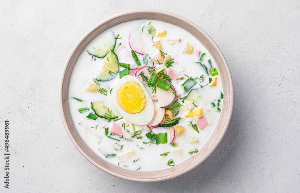 Cold soup with vegetables, egg, fresh herbs and kefir on a gray background. Cold soup with vegetables, egg, fresh herbs and kefir on a gray background.