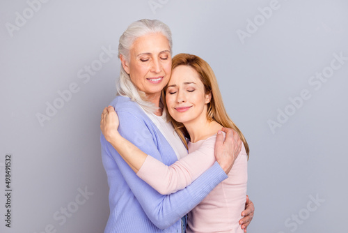 Portrait of two charming woman closed eyes cuddle isolated on pastel grey color background