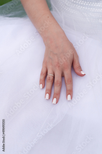 bride's hand with wedding ring on wedding dress