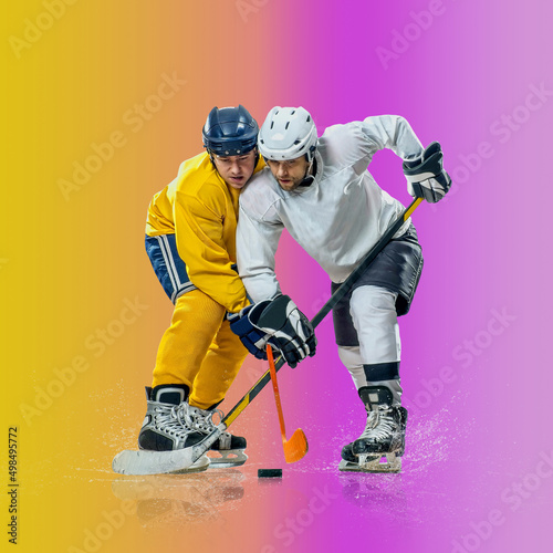 Professional ice hockey player hitting puck for winning goal in action on gradient multicolored neon background. Concept of sport competition.
