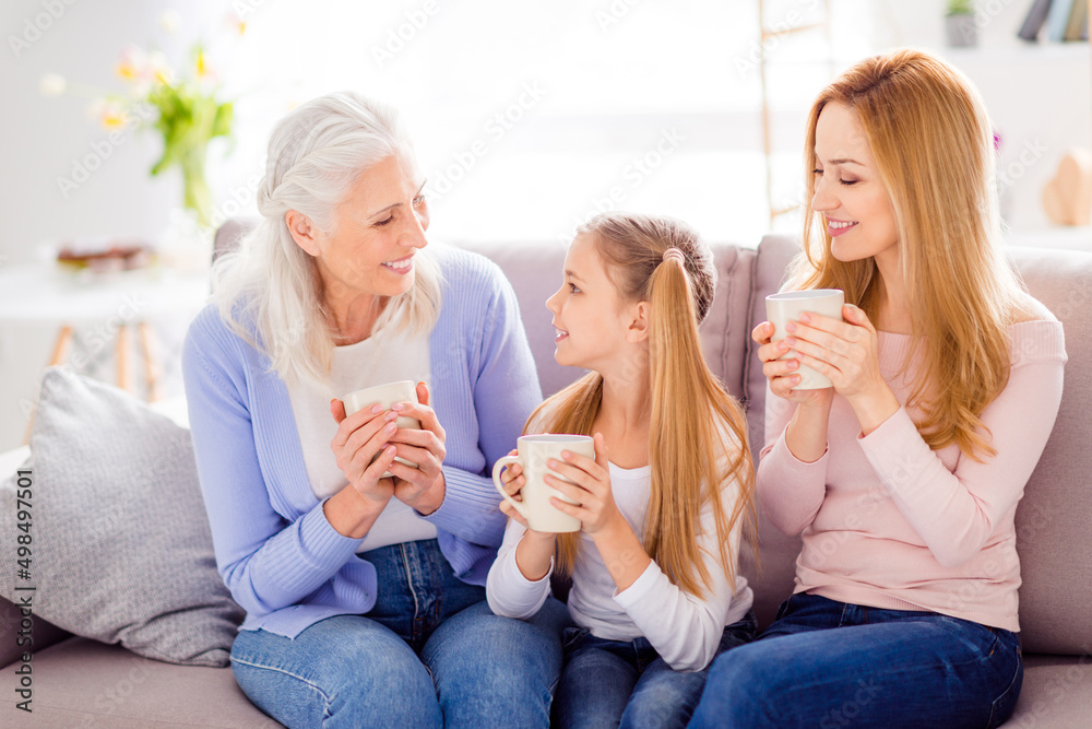 Photo of three friendly idyllic woman hold beverage sitting couch enjoy weekend indoors
