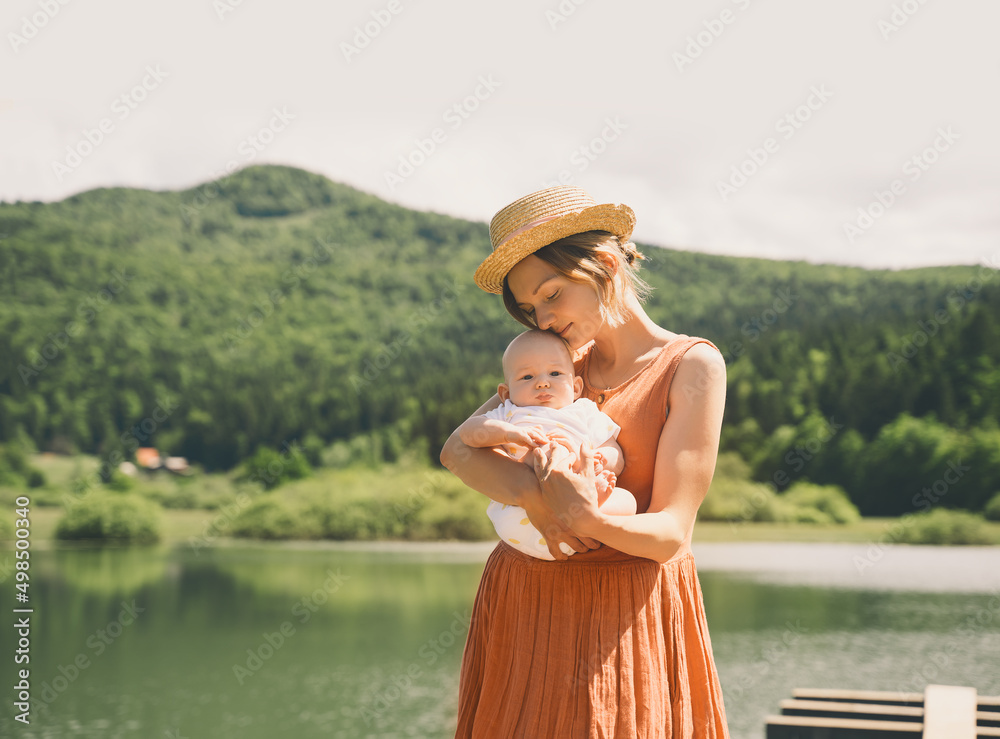 Fototapeta premium Mother and baby. Concept of natural maternity and motherhood. Beautiful woman and little baby happy together in green nature background. Loving mom with child outdoors.