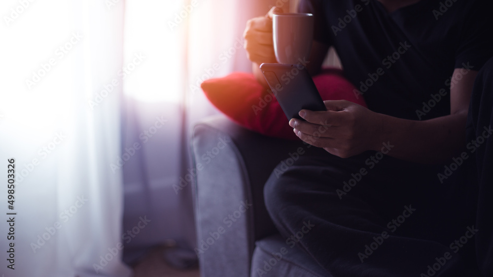 handsome young Hispanic at home drinking coffee and using his smart phone