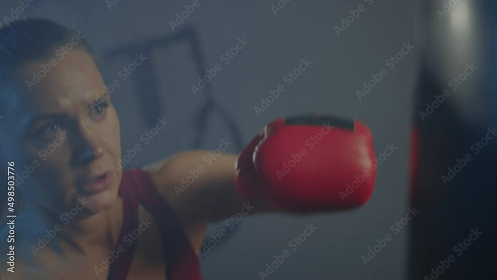 A female boxer trains on a punching bag in the gym. A female boxer trains on a punching bag in the gym.