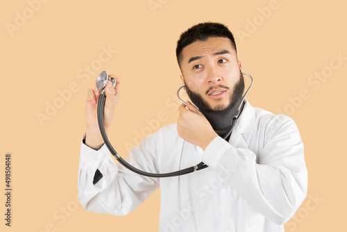 Asian man in Doctor uniform auscultation beige background