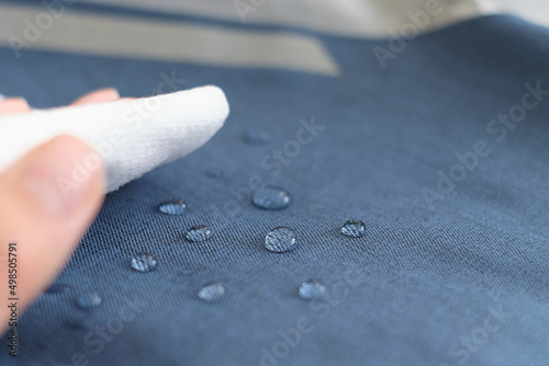 hand wipes drops of water from a cloth. Water drops on waterproof textile material. short depth of field. Waterproof fabric on sofa. photo