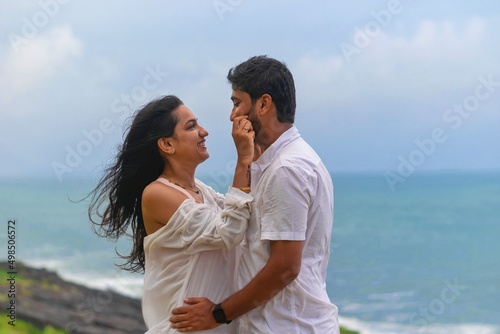  young lovely attractive couple looking at each other, embracing, making love, smiling, cuddling at beach on vacation, holiday, honeymoon, trip to India, Maldives, Asia, foreign beach, cliff, sunset.