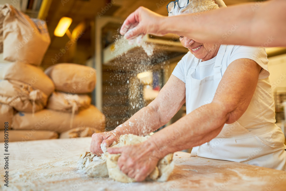 Two bakers knead the dough and sprinkle flour Two bakers knead the dough and sprinkle flour