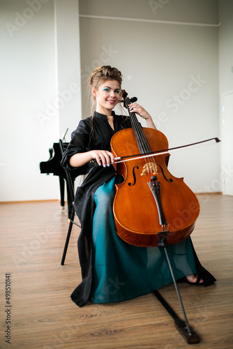 a beautiful girl plays the cello in the classroom, the cello plays and smiles at the camera
