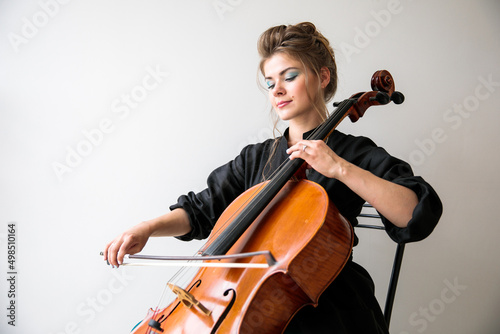 Tela a beautiful girl plays the cello in the classroom against the background of the