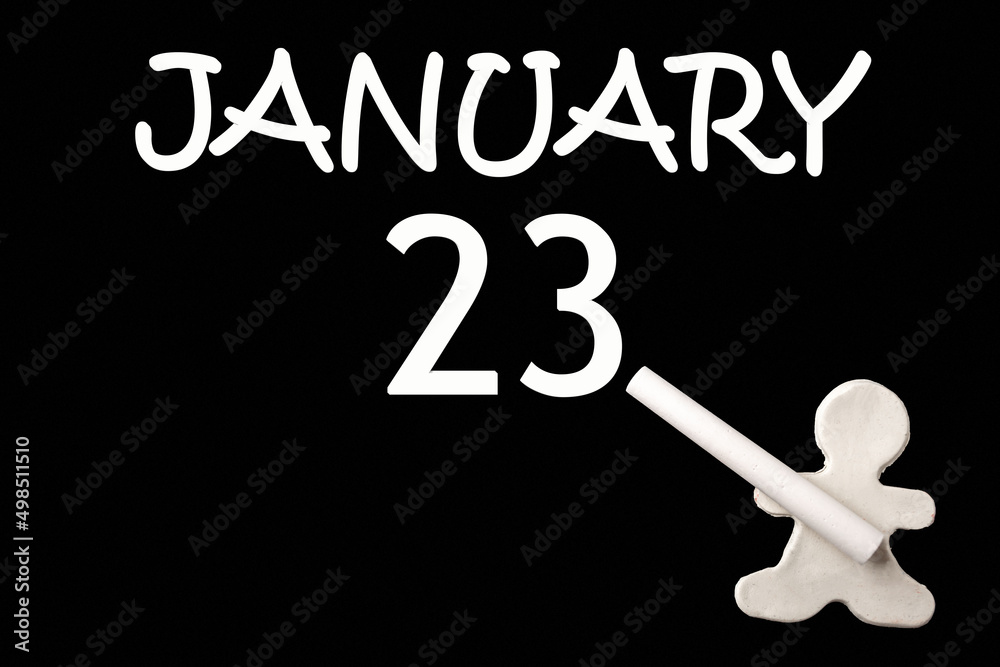 23rd day of January. A small white plasticine man writing the date 23 January on a black board. Business concept. Education concept. Winter month, day of the year concept.