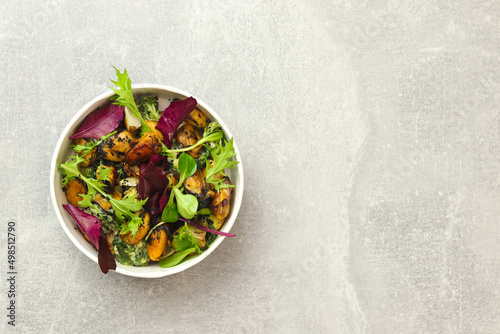Salad with mussels, arugula and greens in a round takeaway paper container on gray background. Healthy food delivery concept. Banner. Top view. Free space for text.
