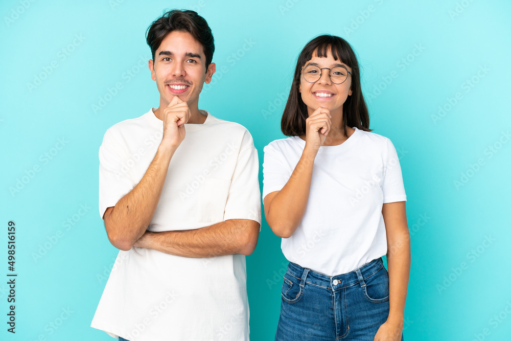 Young mixed race couple isolated on blue background smiling and looking to the front with confident face Young mixed race couple isolated on blue background smiling and looking to the front with confident face