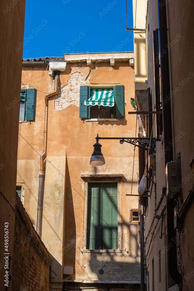 VENICE, ITALY - August 27, 2021: View of windows and doors of houses on the streets of Venice. VENICE, ITALY - August 27, 2021: View of windows and doors of houses on the streets of Venice.