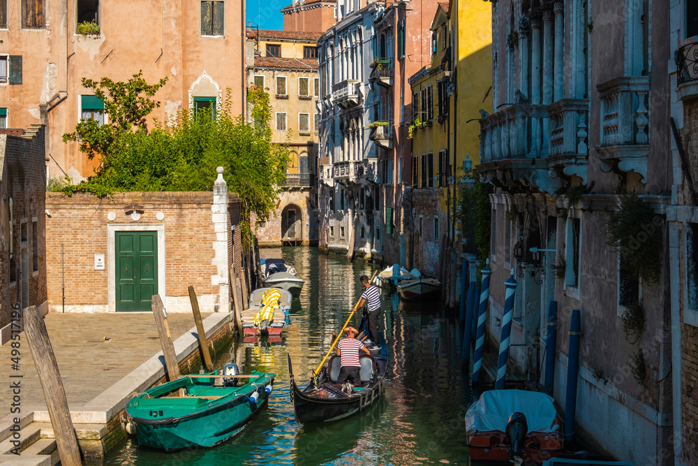 VENICE, ITALY - August 27, 2021:  Gondola sailing on a typical Venetian water street canals