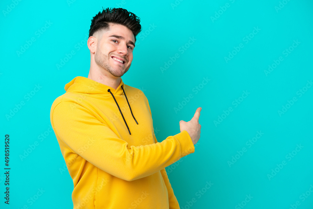Young caucasian man isolated on blue background pointing back Young caucasian man isolated on blue background pointing back