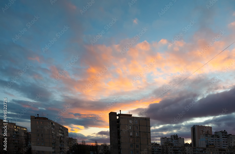 City, large apartment buildings against the background of the evening sky with clouds. Dramatic evening cloudscape in city