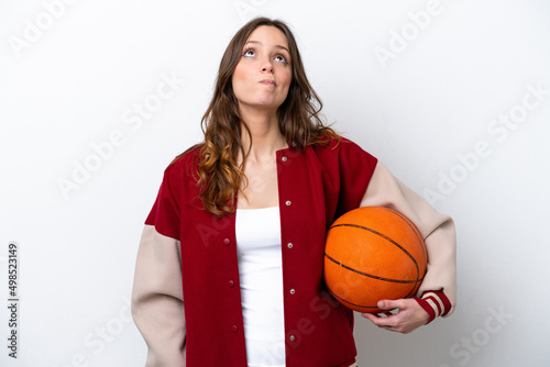 Young caucasian woman playing basketball isolated on white background and looking up