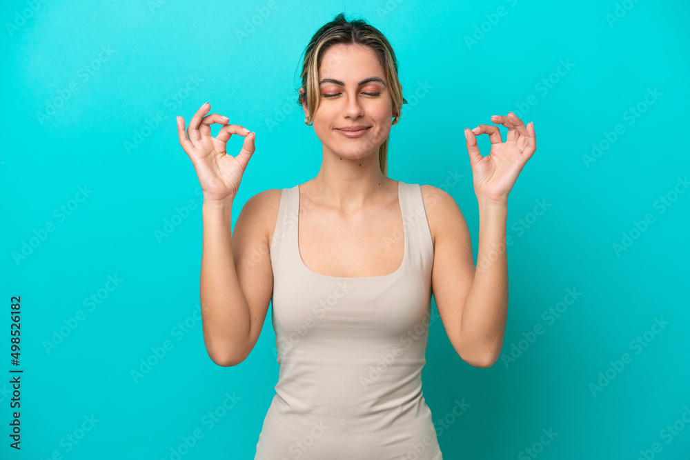 Young caucasian woman isolated on blue background in zen pose Young caucasian woman isolated on blue background in zen pose