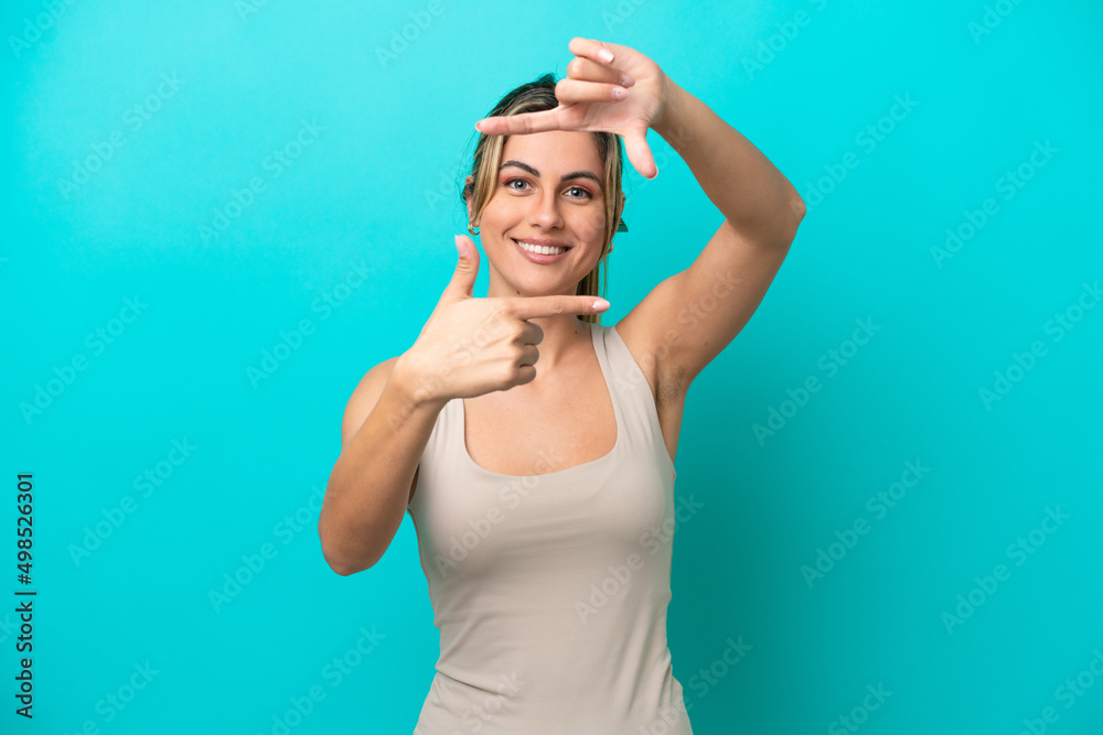 Naklejka premium Young caucasian woman isolated on blue background focusing face. Framing symbol