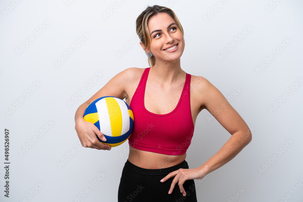 Young caucasian woman playing volleyball isolated on white background posing with arms at hip and smiling