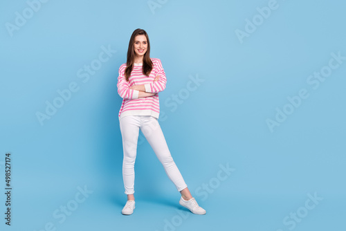 Full length portrait of satisfied glad young person crossed arms toothy smile isolated on blue color background