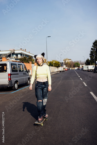 rebel aternative young woman outdoors riding skate skateboarding empty city streets photo