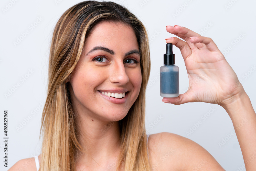Young caucasian woman isolated on white background holding a serum while smiling. Close up portrait Young caucasian woman isolated on white background holding a serum while smiling. Close up portrait